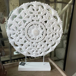Beautiful carved wooden circle panel with a distressed white finish on iron legs and a wooden base.