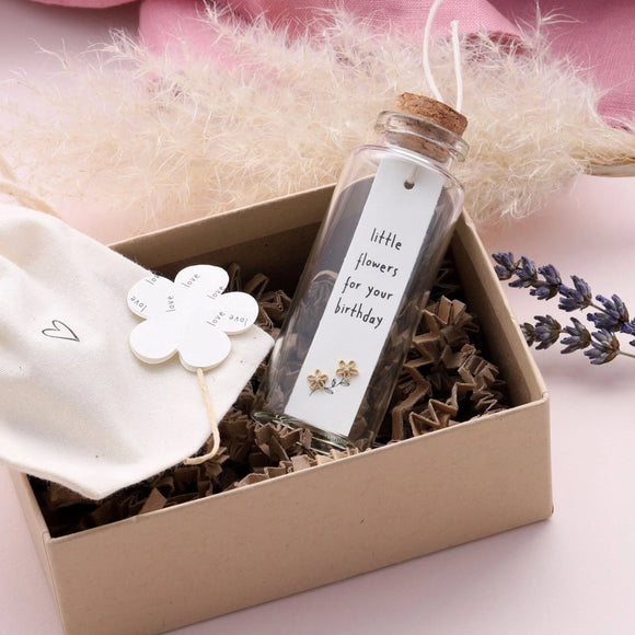 Sweet flower shaped stud earrings presented in a message bottle on a card that reads 